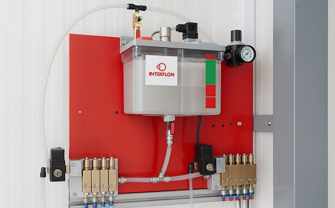 Sistema de lubricación automático rojo rellenado con aceite CLP220 Interflon en cadena de pintado.