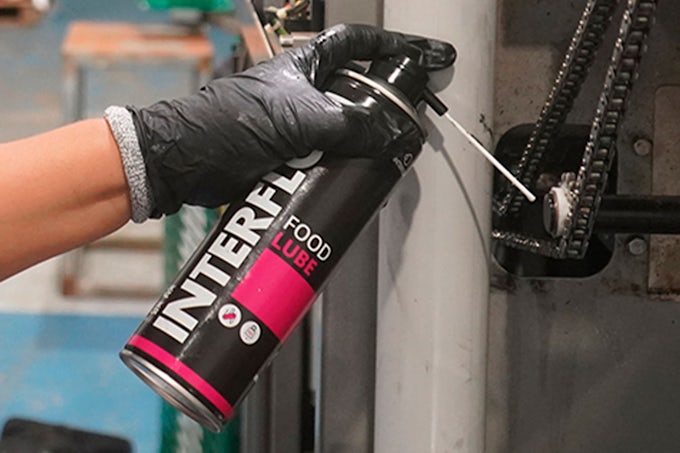 Técnico lubricando cadena industrial con lubricante para cadenas Interflon Food Lube