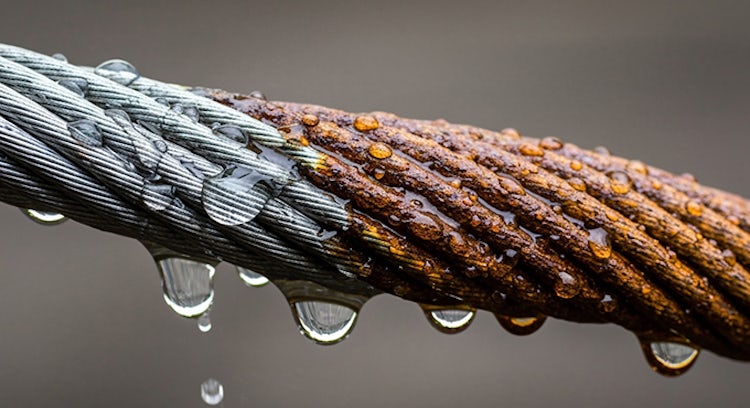 Cable industrial en entorno de humedad y agua. La mitad del cable está bien lubricado y protegido, la otra mitad está oxidado.