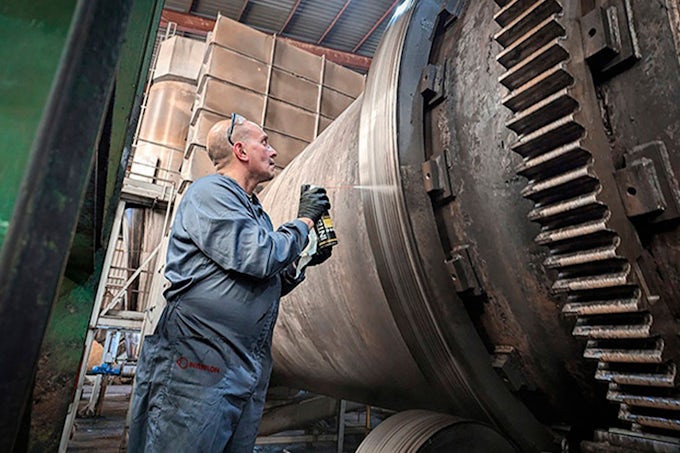 Técnico de mantenimiento lubricando engranajes industriales de grandes dimensiones