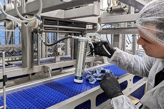 Lubricación de rodamiento en maquinaria mediante pistola de engrase con grasa alimentaria.