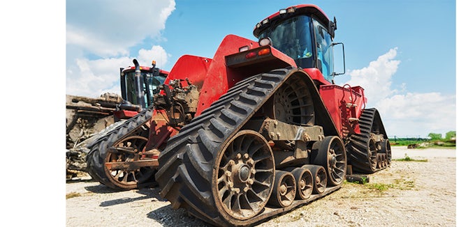 Máquina agrícola roja en un entorno rural, donde se ven sus grandes ruedas y mecanismos que están sometidos a alta presión