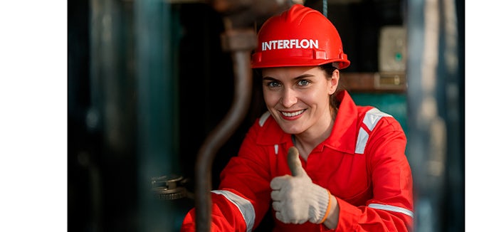 Técnico de mantenimiento industrial de Interflon aplicando lubricante especializado en maquinaria pesada y subiendo el pulgar hacia arriba afirmando que todo es correcto.